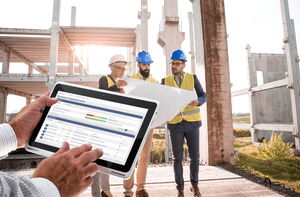 Bauplanungsteam auf der Baustelle mit Tablet und tick-at-time im Vordergrund