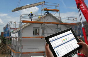 Haus im Umbau mit Tablet und Screen von tick-at-time im Vordergrund