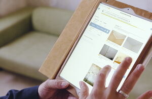 Im Vordergrund Tablet mit der GebäudeCheck App und im Hintergrund eine Couch