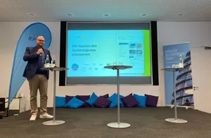 Präsentationsituation einer Person auf Bühne und großem Screen